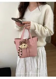 Detail of pink bucket bag with lychee texture and cute poodle charm accessory