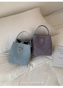 Detail of retro bucket bags in morandi blue and purple with metal cross turn-locks