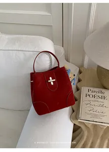 Detail of vintage red suede bucket bag with silver metal twist lock on white sofa