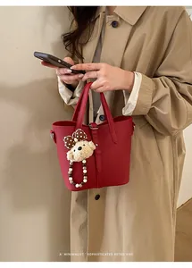 Detail of red pebbled leather bucket bag featuring a cute plush bear charm decoration