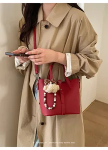 Detail of red pebbled leather bucket bag with a cute plush puppy charm accessory