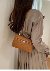 Détail de la texture en cuir tressé marron et détails argentés du sac à bandoulière