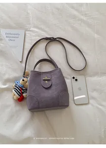 Detailed top view of purple bucket bag with metal lock, plush charm, and size reference