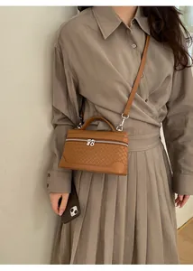 Gros plan d'un sac à main tressé marron avec double fermeture éclair et bandoulière