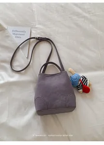 Detailed top view of purple bucket bag with a cute crochet doll charm on soft cloth