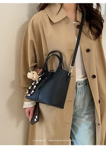 Close-up of black leather bucket bag with litchi texture and cute teddy bear charm