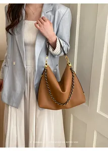 Detail of caramel leather tote bag with gold chain strap on light blue blazer