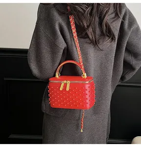 Detail of red quilted box bag with tonal rivets and elegant gold chain strap detail