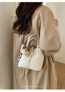 Detailed texture of white lychee leather bucket bag with cute plush bear charm accessory