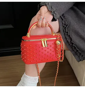Detail of red quilted box bag with bead studs, gold metal handle and star ball chain