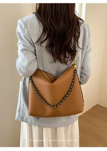Rear view of brown litchi leather tote bag with metal chain strap on a model