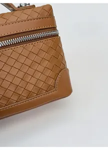 Détail de la texture en cuir tressé marron avec une fermeture éclair en métal argenté