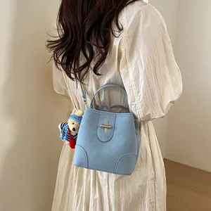 Light blue bucket bag in matte leather featuring gold cross lock and cute bear charm