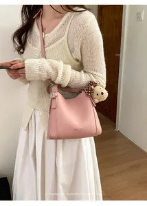 Detail of light pink bucket bag with leather texture and cute bear charm accessory