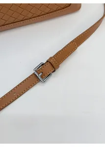 Détail du sac bandoulière marron tressé avec sangle réglable et boucle en métal argenté