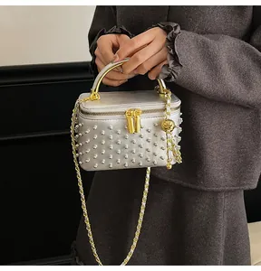 Detail of silver box bag with metallic studs, gold chain strap and bead charm