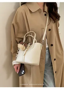 Close-up of minimalist beige bucket bag with lychee pattern and cute dog pendant