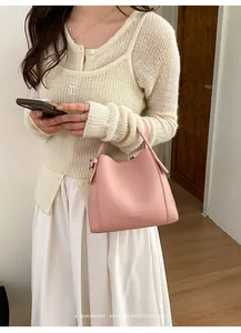 Detail of pink bucket bag with leather texture and minimalist metal hardware