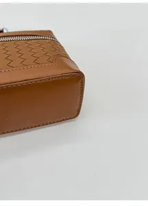 Détail de la base large d'un sac à main en cuir tressé marron avec fond plat et fermeture