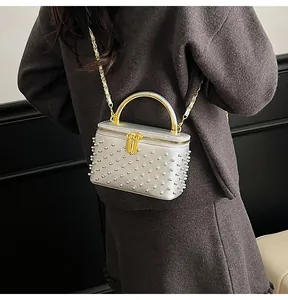 Detail of silver box bag featuring white pearls, gold handle and leather chain strap