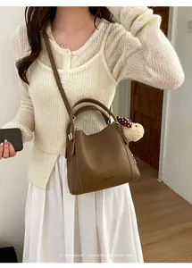 Brown lychee leather bucket bag with cute dog pendant and adjustable shoulder strap