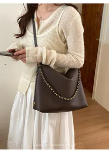 Detail of dark brown pebbled leather tote bag with elegant gold-tone chain strap