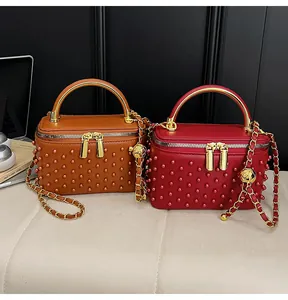 Close-up of pearl-embellished vanity box bags in brown and red with gold metal handles