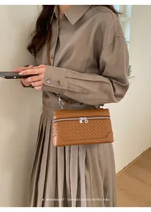 Détail du sac à main tissé marron avec poignée supérieure et boucles en métal argenté