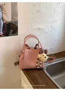 Detailed texture of pink litchi grain leather bucket bag with cute bear charm
