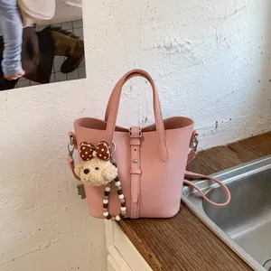 Pink lychee grain leather bucket bag with a cute bear charm and crossbody strap