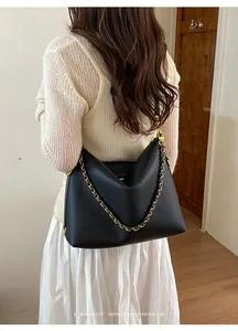 Detail of black lychee grain leather tote bag with gold chain and minimalist retro design