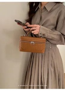 Détail du sac à main tissé caramel avec poignée supérieure élégante et fermeture éclair double