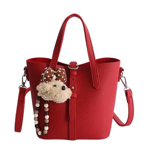 Red lychee pattern leather bucket bag with cute bear charm and adjustable shoulder strap