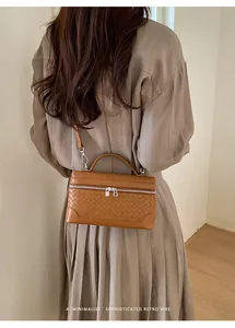 Détails de la texture en cuir tressé marron d'un sac à bandoulière rétro avec boucle argentée