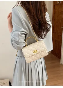 Detailansicht der cremeweißen Stepptasche mit goldenem Metallgriff und Kettenriemen
