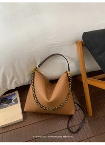 Close-up of tan hobo bag with litchi texture leather, woven chain and gold hardware