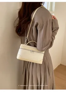 Gros plan d'un sac bandoulière beige crème en cuir tressé porté par un mannequin