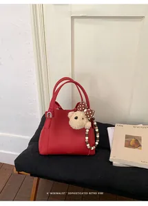 Detail of red bucket bag with lychee grain leather, teddy bear charm and beaded chain