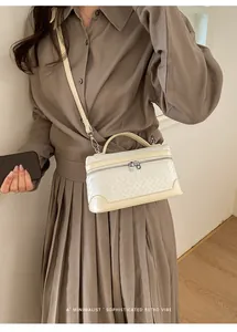 Détail du sac tressé crème avec coins renforcés et bandoulière amovible élégante