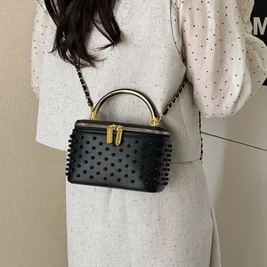 Elegant black beaded chain box bag with golden handle worn by a model in casual style
