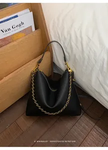 Close-up of black lychee grain leather tote with gold chain strap and hobo design