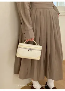 Détail d'un sac à main tissé crème rectangulaire avec poignée et fermeture éclair argentée