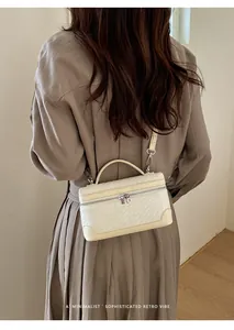 Petit sac carré chic en cuir tressé crème porté à l'épaule au style rétro