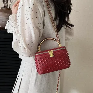 Red mini box bag with rivets, gold handle and chain strap for elegant crossbody look