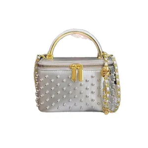 Silver quilted crossbody box bag with gold handles and decorative silver studs
