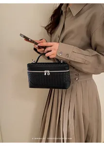 Détail du sac à main en cuir tressé noir avec poignée supérieure et zip argenté bidirectionnel
