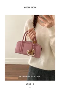 Pink Boston handbag with a wooden horse charm shown with a white sweater and grey skirt