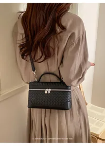 Détail d'un sac à main noir en cuir tressé avec double fermeture éclair et bandoulière