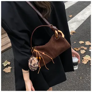 Detail of vintage brown suede pillow bag featuring gold metal chain and leopard print charm