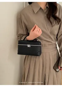 Détail du sac à main noir en cuir tressé avec fermeture éclair argentée et poignée